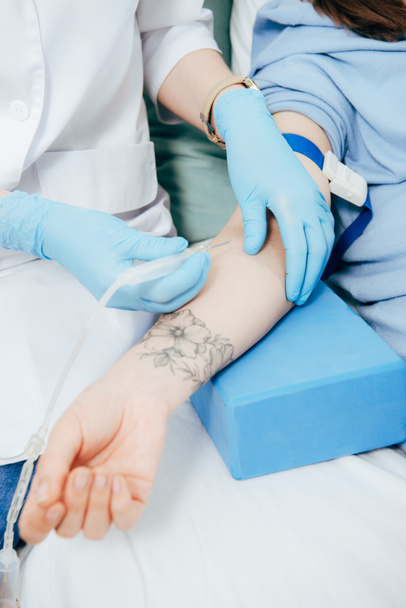 bijgesneden weergave van de arts in latex handschoenen doen injectie in het ziekenhuis - Foto, afbeelding