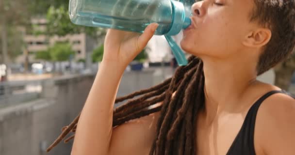 Side view of young African American woman drinking water in the city. She is exhausted and tired 4k - Πλάνα, βίντεο