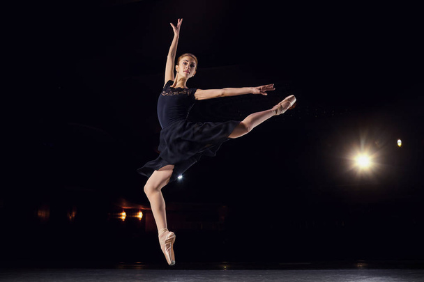 Ballerina in a black suit is jumping on a black background. - Fotoğraf, Görsel