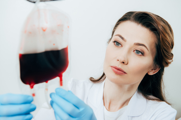 lekarz w Rękawice lateksowe trzymając worek krwi na białym - Zdjęcie, obraz