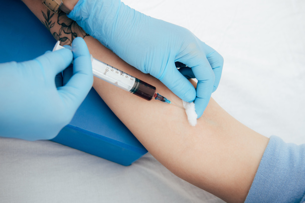 vista cortada de doador e médico com seringa obtenção de amostra de sangue
 - Foto, Imagem