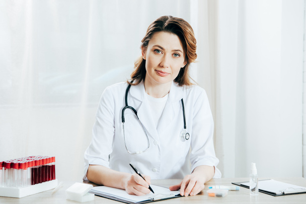 dokter in witte vacht schrijven op Klembord in kliniek - Foto, afbeelding