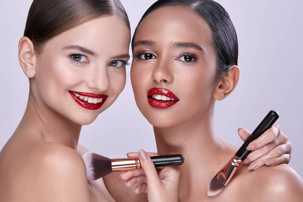 Porträt junger schöner Frauen, die mit Make-up-Pinseln posieren - Foto, Bild