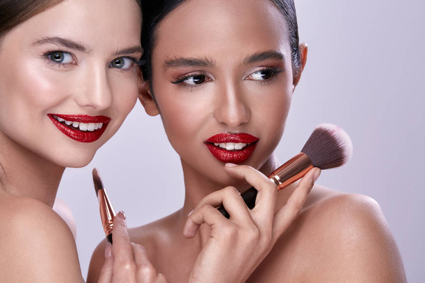portrait of young beautiful women posing with makeup brushes - Foto, Imagen