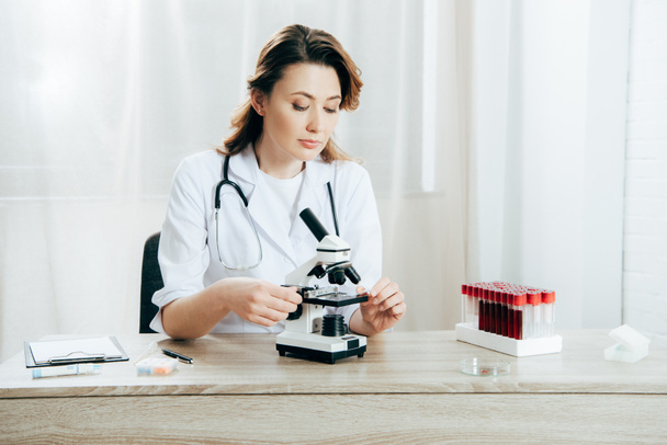 Doktor v bílém plášti s použitím mikroskopu na klinice - Fotografie, Obrázek
