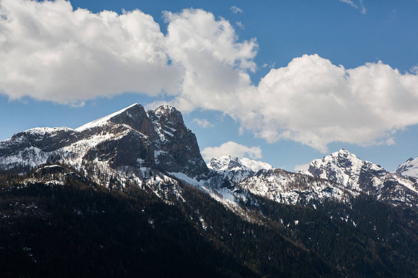 Malowniczy widok na śnieżny szczyt góry w słoneczny dzień z błękitne niebo i dramatyczne chmury w tle, Włochy, Dolomiti. Piękne górskie krajobrazy w Alpach  - Zdjęcie, obraz
