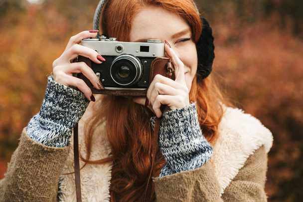 Lovely redheaded young girl listening to music, holding photo camera - Фото, зображення