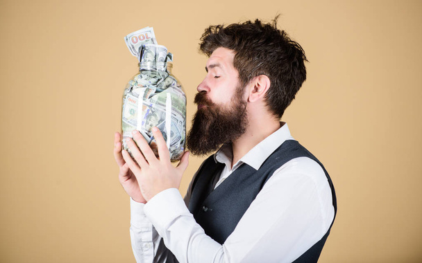 Attractive investment. Bearded man investor kissing glass jar with investment money. Successful businessman making a good investment. His investment producing income - Photo, image
