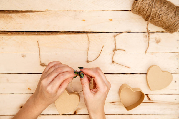 ženské ruce roztahují srdce a slovo láska k vláknům na lehkém dřevěném pozadí. pohled shora - Fotografie, Obrázek
