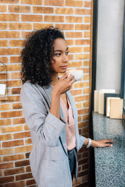 オフィスでコーヒーを飲むアフリカ系アメリカ人カジュアルビジネスウーマン - 写真・画像