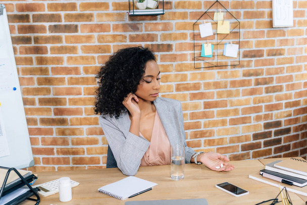 african american Casual businesswoman with pills and glass of water at office desk  - Photo, Image