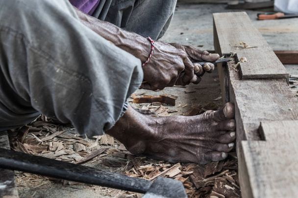 Close up van waarschuwen handen van timmerman werken in traditionele handmatige timmerwerk shop in een derde wereldland. - Foto, afbeelding