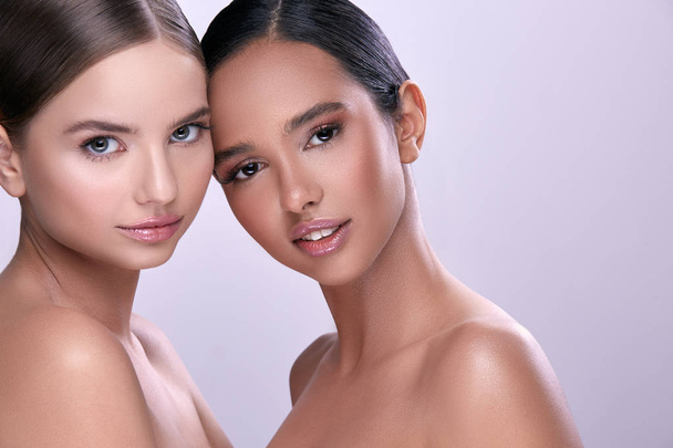Porträt junger schöner Frauen mit nacktem Make-up, die vor violettem Hintergrund posieren - Foto, Bild
