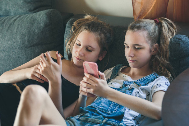 Young women using mobile phones watching music clip, texting, me - Φωτογραφία, εικόνα