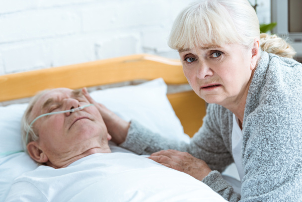 rozrušená starší žena a muž v kómatu na klinice - Fotografie, Obrázek