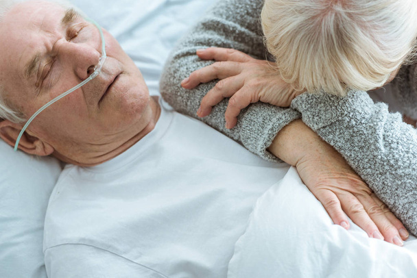 обрезанный вид бессознательного пожилого мужчины и грустной жены в клинике
 - Фото, изображение