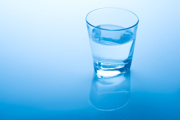 青い背景の水のガラス - 写真・画像