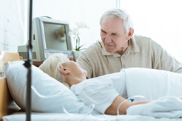 άρρωστη ηλικιωμένη γυναίκα με σύζυγο να κοιτάζει ο ένας τον άλλον στην πτέρυγα της κλινικής. - Φωτογραφία, εικόνα
