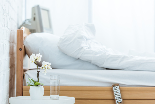 empty bed, orchids and glass of water in hospital ward - Foto, imagen