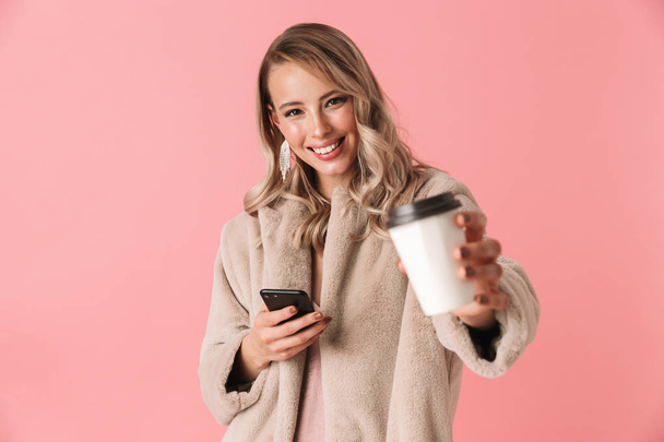 Happy blonde woman wearing in fur coat holding smartphone - Фото, зображення