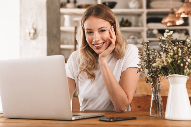 Portrait of pretty blond woman working on laptop and resting whi - Foto, afbeelding