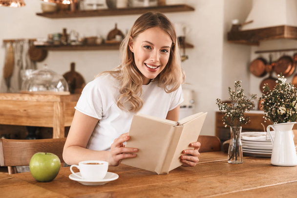 Portrait of young blond woman reading book and drinking coffee w - Zdjęcie, obraz