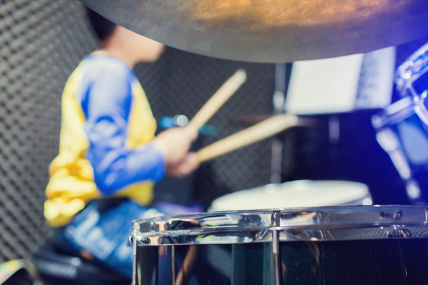 drewniane pałeczki perkusyjne w rękach azjatyckiego dzieciaka noszącego niebiesko-żółte  - Zdjęcie, obraz