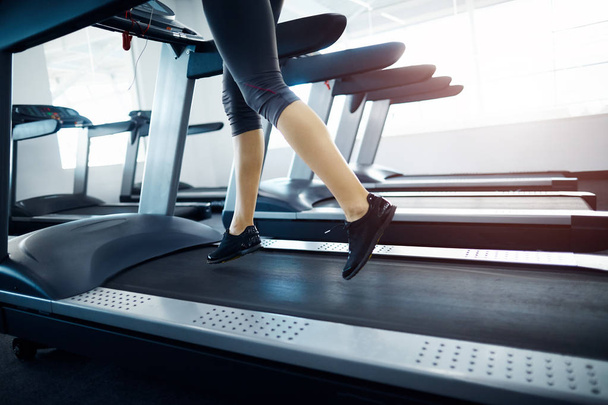 vista parcial de la mujer haciendo ejercicio en la cinta de correr en el gimnasio
 - Foto, imagen