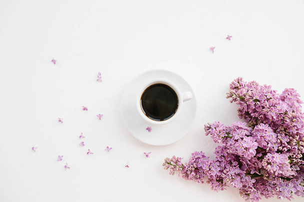 Cup of coffee and lilac branch on white textured background - Photo, Image