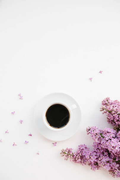 Cup of coffee and lilac branch on white textured background - Fotó, kép