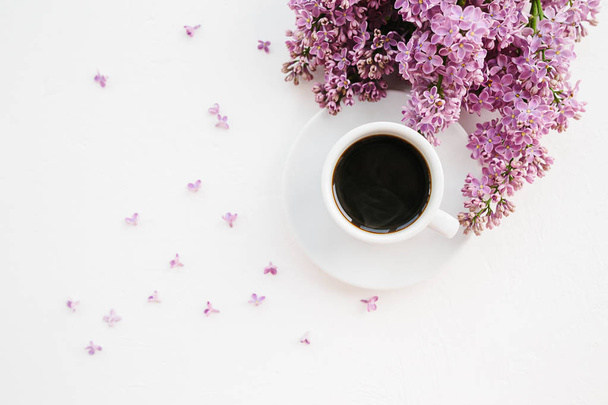 Cup of coffee and lilac branch on white textured background - Foto, Imagen