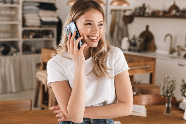 Portrait of satisfied blond woman talking on cell phone while st - Photo, image