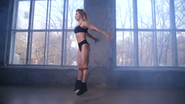 Sportos nő csinál ugrani zömök a rugalmas sáv - Felvétel, videó