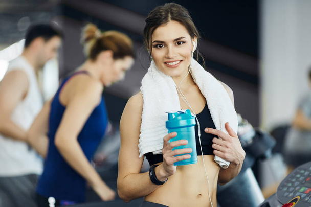 молодая женщина с бутылкой воды тренировки в тренажерном зале
 - Фото, изображение