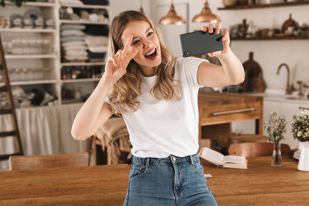 Portrait of young blond woman taking selfie photo on smartphone  - Foto, immagini