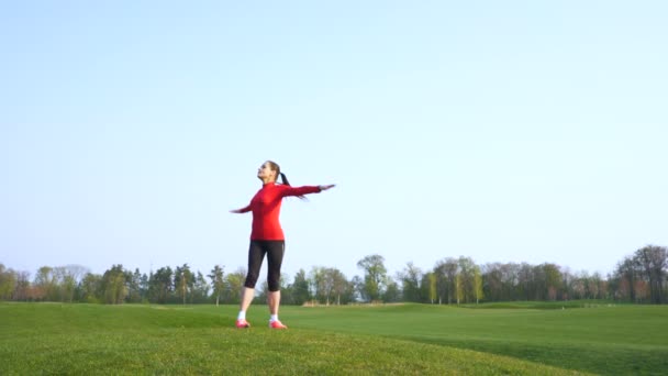 4K. Fitness-nainen tekee urheiluharjoituksia, kehon lämmittelyä vihreällä kentällä
. - Materiaali, video
