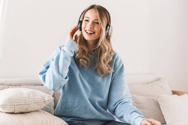 Portrait of pleased blond girl 20s wearing headphones smiling an - Фото, зображення