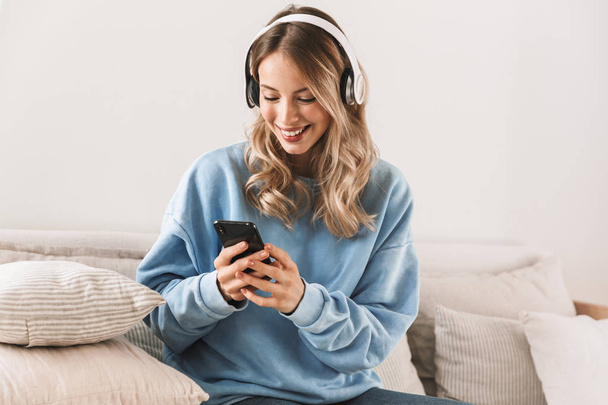 Portrait of attractive blond girl 20s wearing headphones using s - Foto, afbeelding