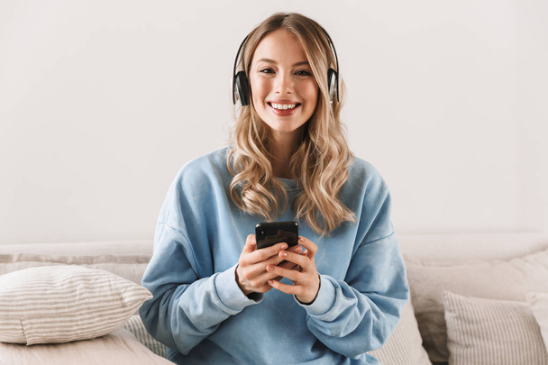 Portrait of young blond girl 20s wearing headphones using smartp - Foto, immagini