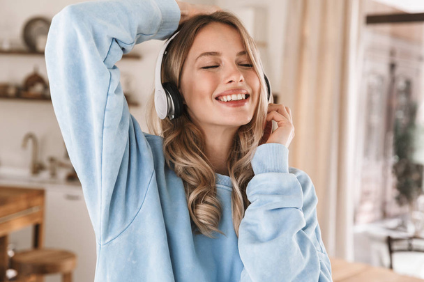Portrait of beautiful blond girl 20s wearing headphones listenin - Фото, зображення