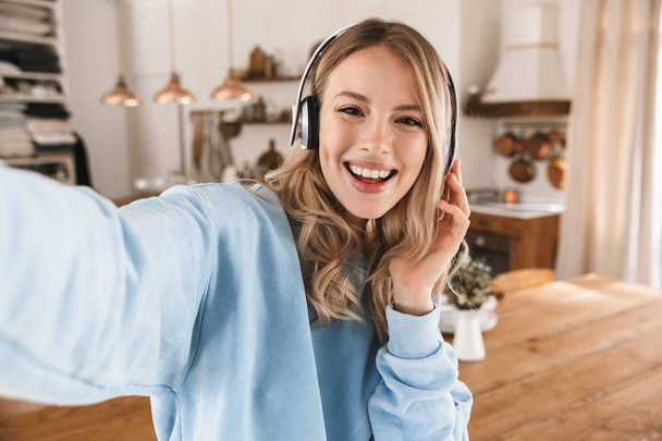 Portrait of attractive blond girl 20s wearing headphones smiling - Foto, imagen
