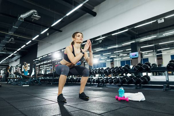 Sportlerin hockt allein im Fitnessstudio - Foto, Bild