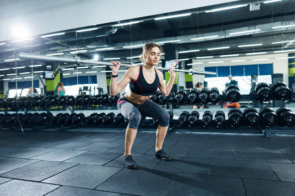 athletic sportswoman squatting in gym alone - Photo, Image