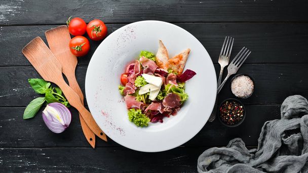 Vegetable salad with brie cheese and prosciutto. In the plate. Top view. Free space for your text. Rustic style. - Photo, Image