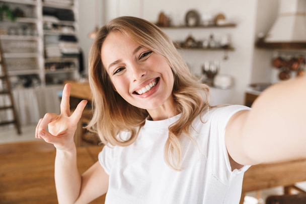 Image closeup of pretty blond woman showing peace sign while tak - 写真・画像