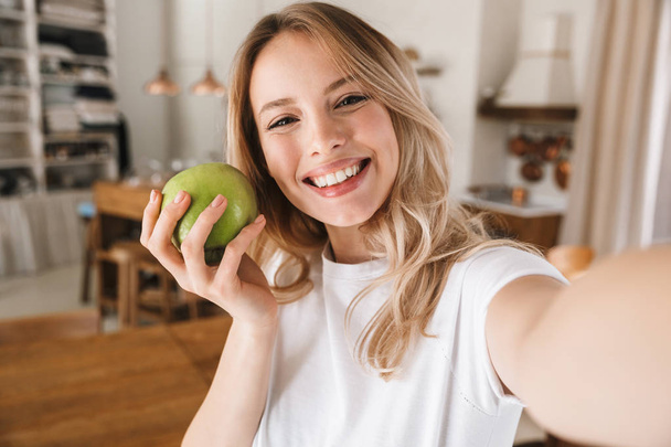 Image closeup of attractive blond woman laughing and holding gre - Foto, afbeelding