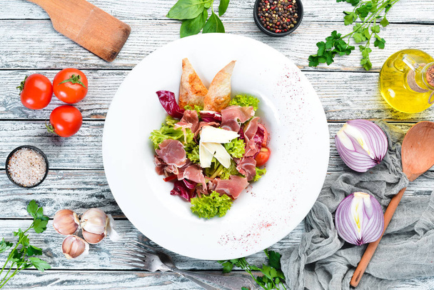 Vegetable salad with brie cheese and prosciutto. In the plate. Top view. Free space for your text. Rustic style. - Foto, afbeelding