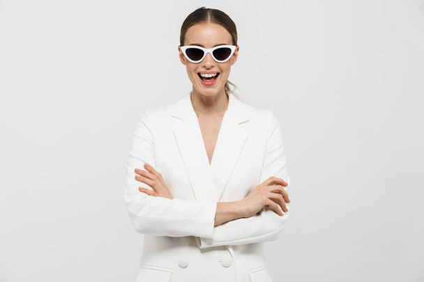 Beautiful happy woman posing isolated over white wall background wearing sunglasses. - Photo, image