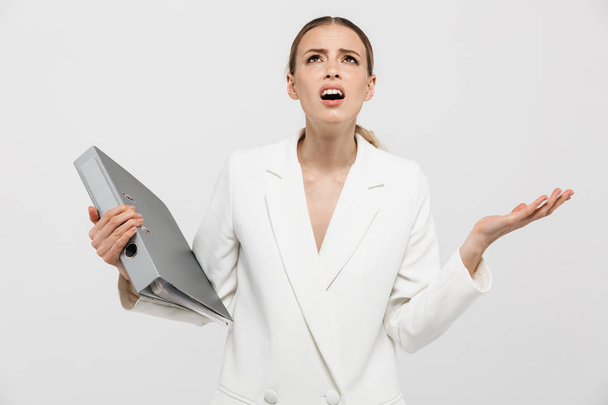Beautiful displeased nervous woman posing isolated over white wall background holding folder. - Foto, immagini