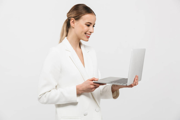 Beautiful happy amazing woman posing isolated over white wall background using laptop computer. - Photo, image